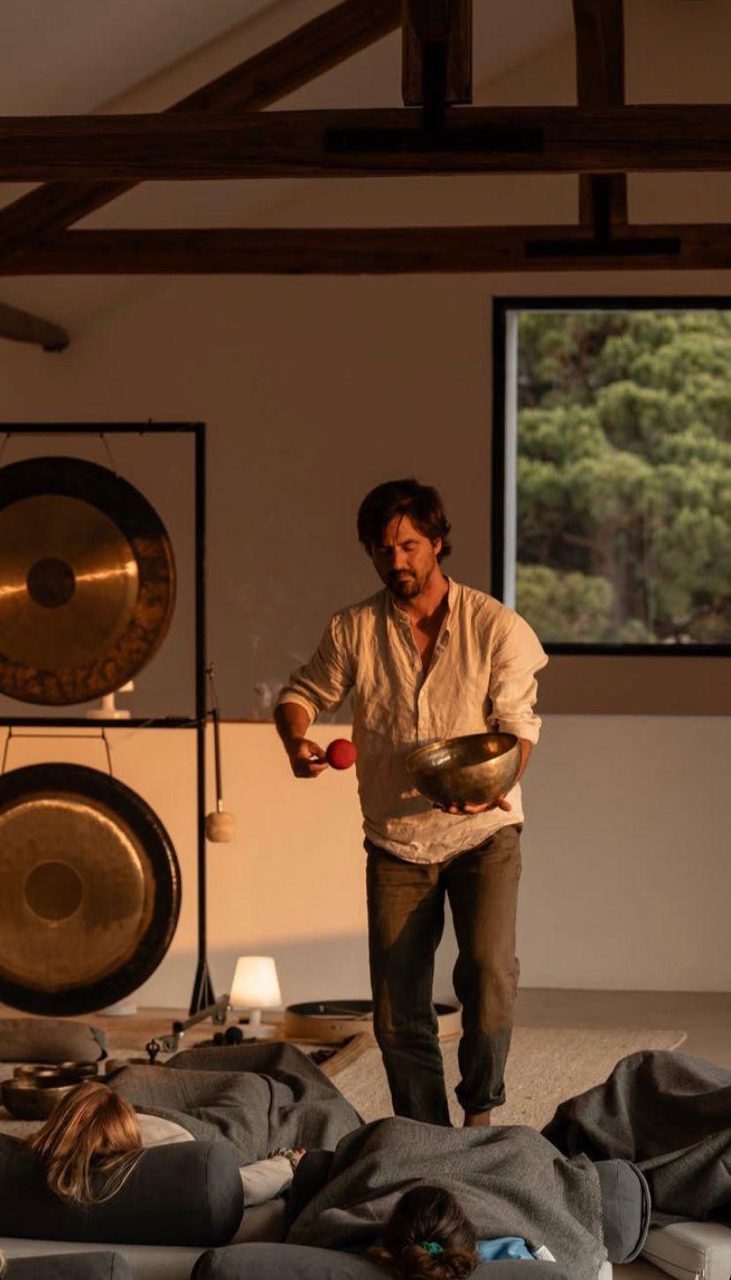 Francisco walking among resting participants with a singing bowl