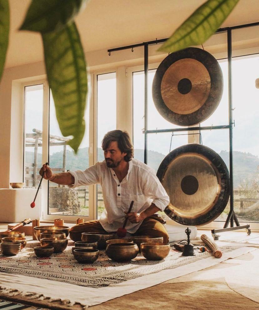 Francisco playing singing bowls in front of two gongs